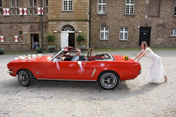 Braut schiebt Ford Mustang am Schloss Broich